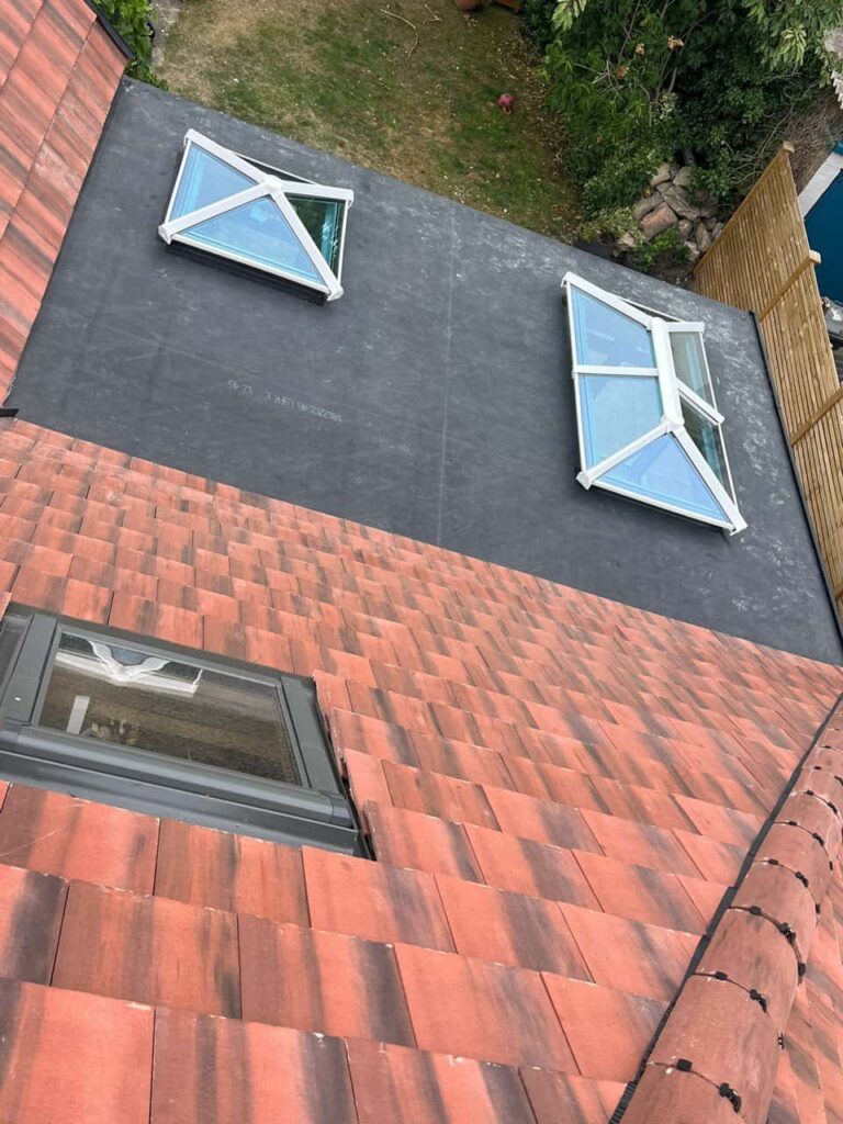 This is a photo taken from the roof ridge looking down a tiled pitched roof on to a flat roof. Works carried out by Wingerworth Roofing Repairs